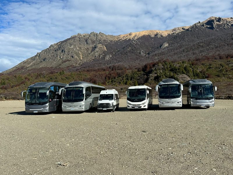 Flota de De Sur a Sur estacionada al pie de la cordillera: buses, minibús y combi